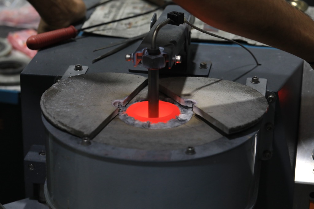Glowing red-hot molten gold vacuum induction casting furnace in operation