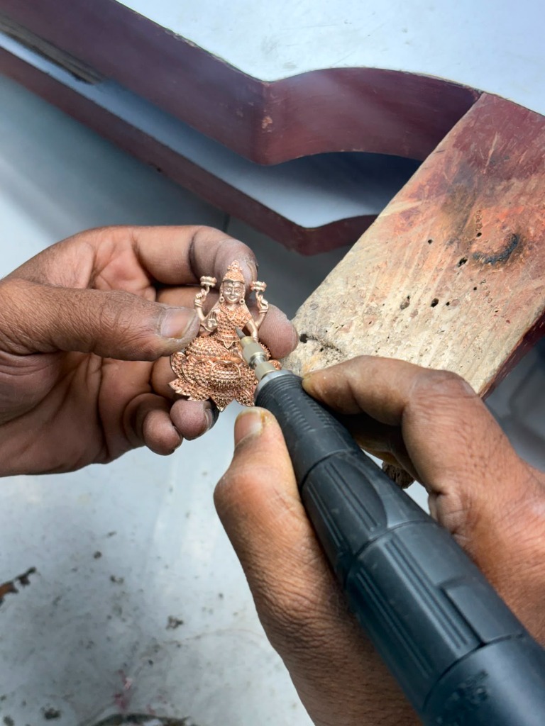 Goldsmith using precision rotary micro-burr tool to hand-refine gold Lakshmi idol motif