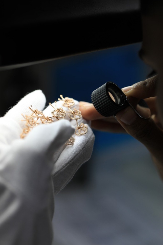Quality inspector with white gloves reviewing diamond pavé floral cluster with 10x magnification loupe